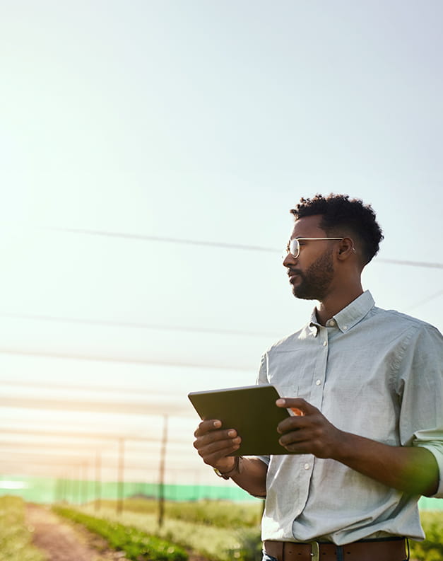 A man surveying a field with a tablet in his hand