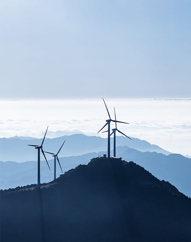 A shadow-like image of wind turbines in action on top of a hill on a cloudy day