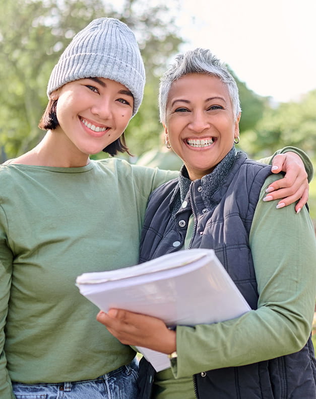 Two women stand together, wearing matching t-shirts. One has their arm around the other in a show of togetherness