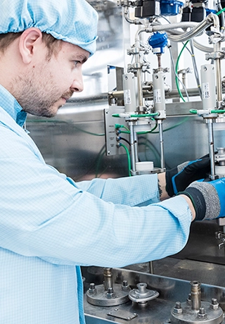 A man wearing a hair covering, overalls and gloves is inspecting equipment