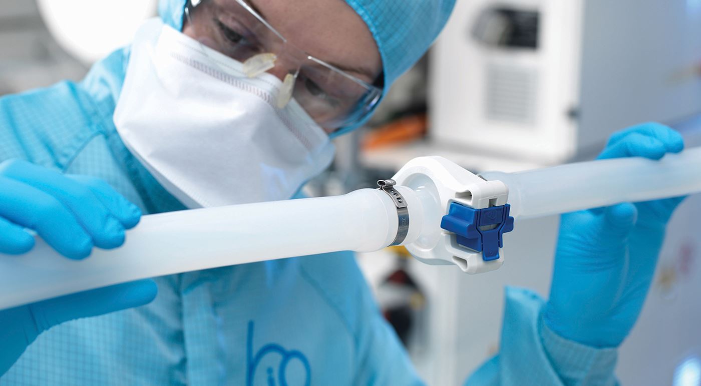 A Biopure colleague is assessing a pipe in a clean environment, wearing a mask, hair covering and glasses 