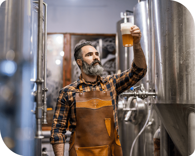 A brewer holds up a sample of beer to the light to assess