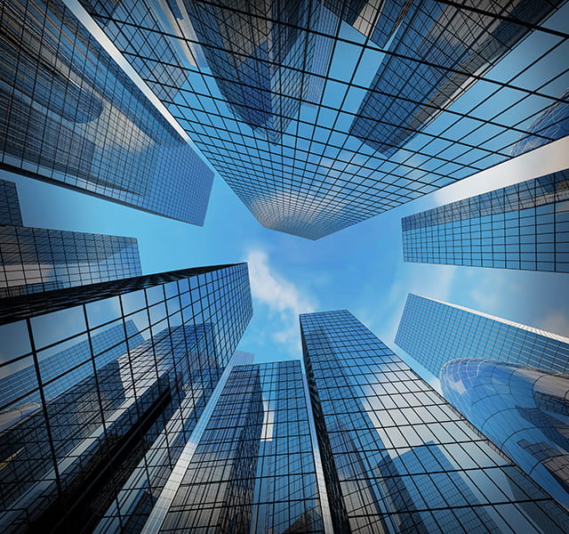A floor-level view of sky-scraper type buildings surrounding the camera