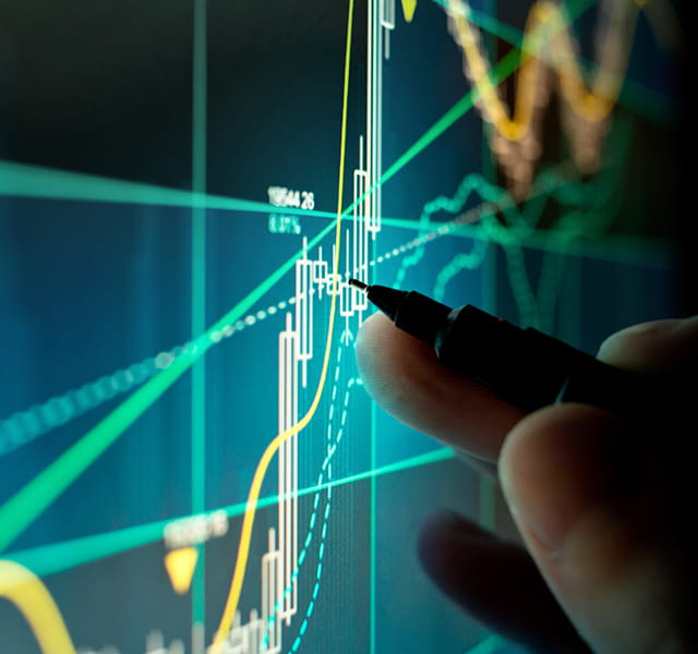 A hand with a pen is hovering over a digital line graph