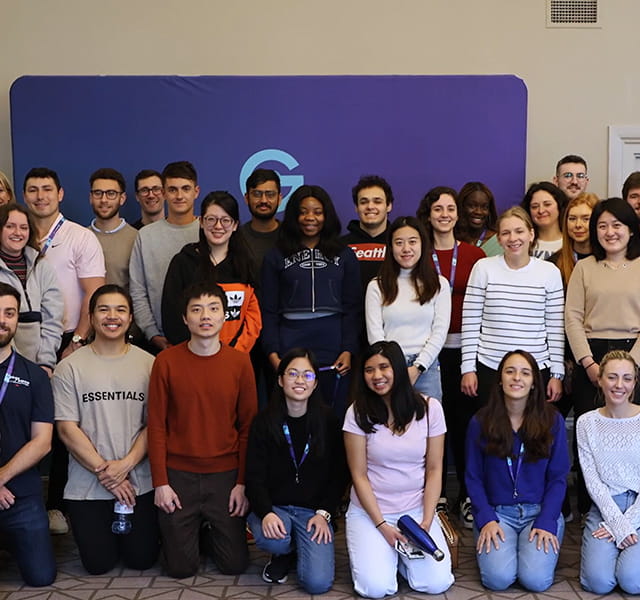 A group picture of our Global Graduate cohort at our GradCon 2023 event standing in front of a purple background. 