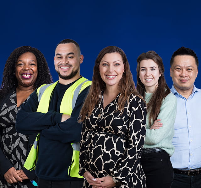 Five colleagues from different cultural backgrounds are standing together in front of a blue background