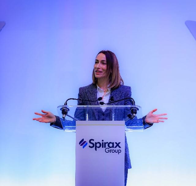 Maria Wilson talking at a podium with her hands outstretched