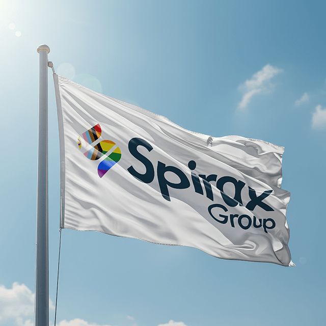 A white flag flies in the wind amongst a blue sky. It has the Spirax Group logo with the S in the colours of the Pride flag. 