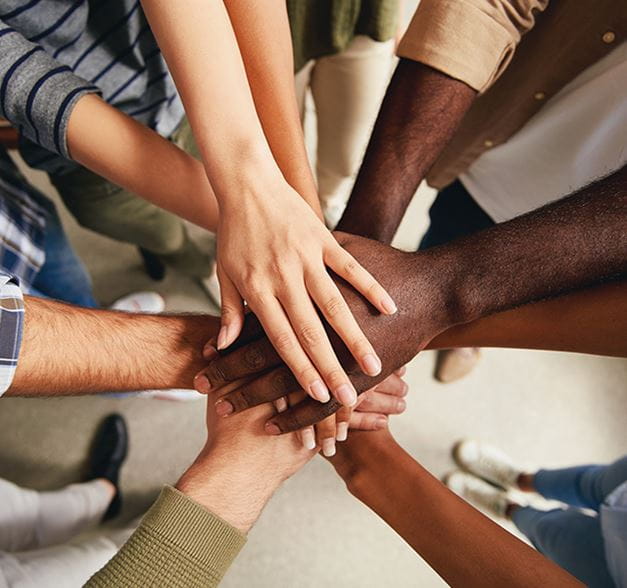 A multicultural image of people stacking their hands in celebration