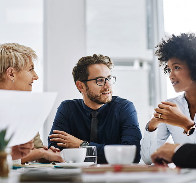 Three people in a meeting room having a discussion. 