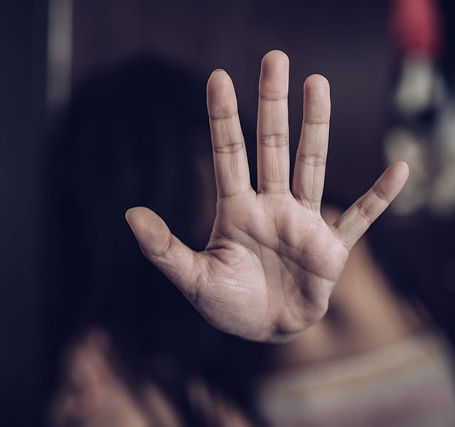 A hand is held up outstretched in a 'stop' signal to a dark background
